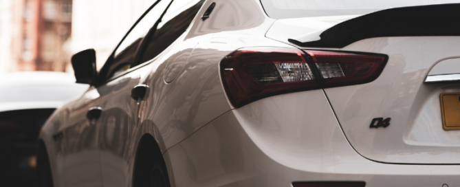 Rear view of a white sedan parked on a city street, representing a private car sale purchase.