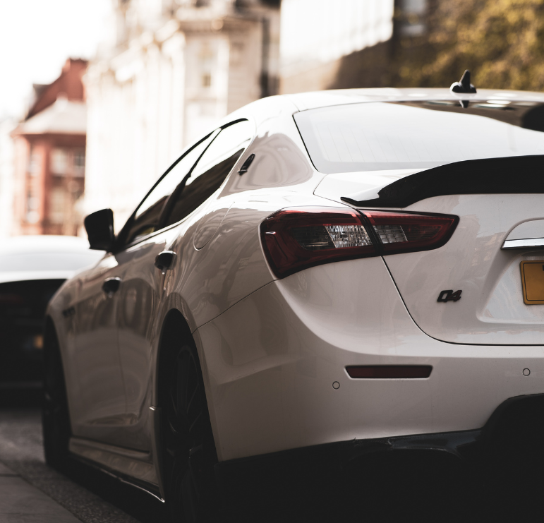 Rear view of a white sedan parked on a city street, representing a private car sale purchase.